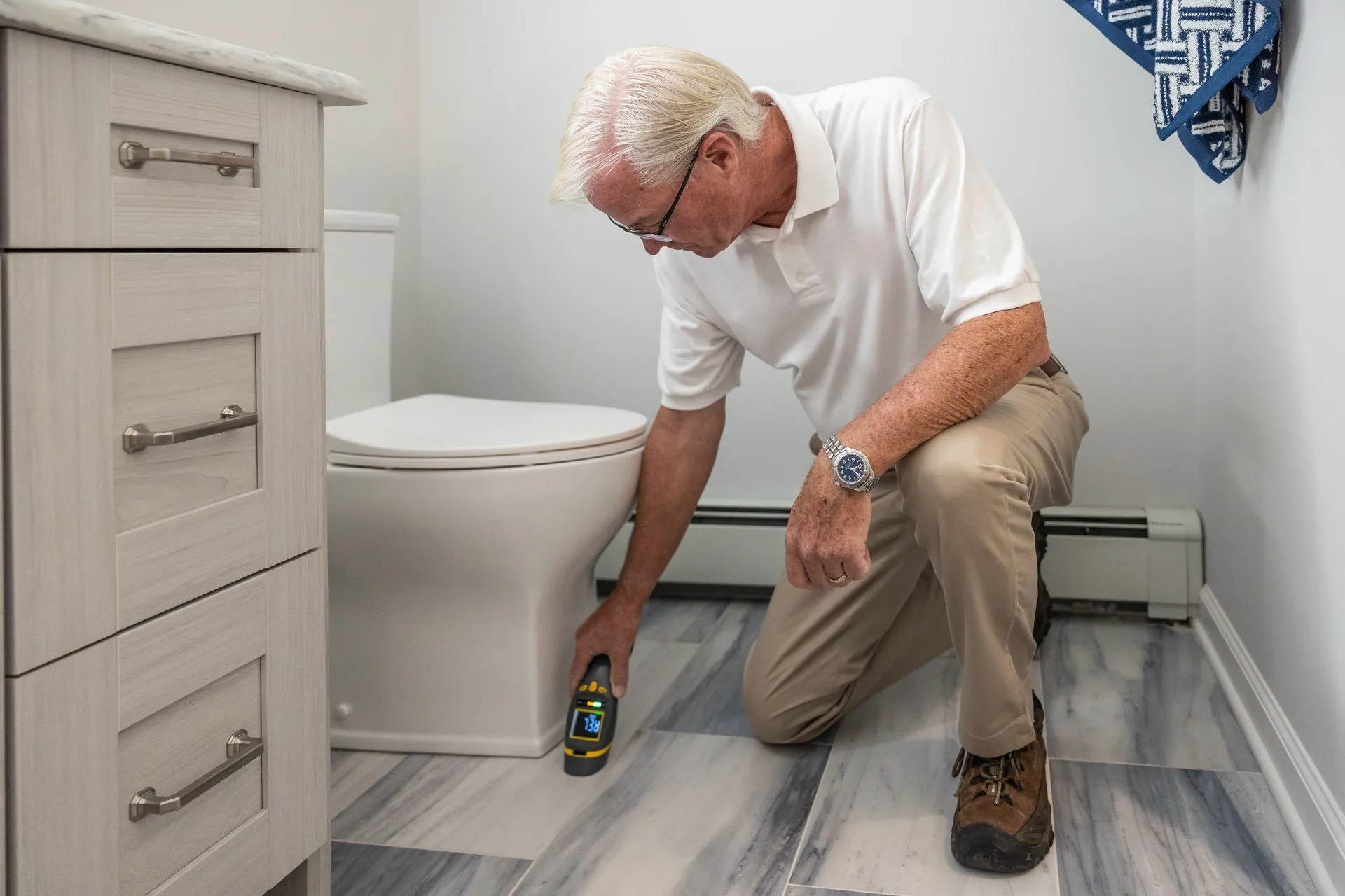 Homeowner checking the floor beside a toilet with a handheld meter