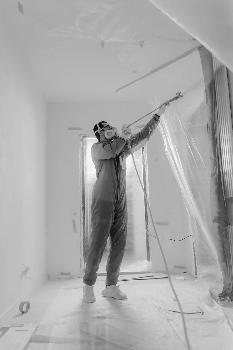 Worker inside a plastic-sheeted containment during interior work